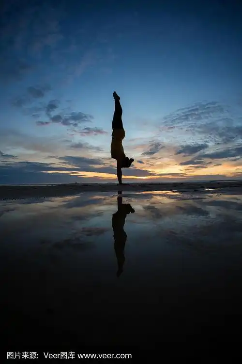 日落时分,一个女孩在海滩上做倒立