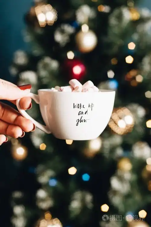 女人手拿着美味的甜棉花糖在白色的杯子里