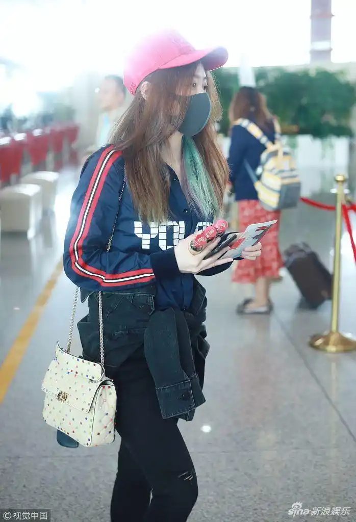 张靓颖戴小红帽赶早班机 戴口罩一路低头玩手机