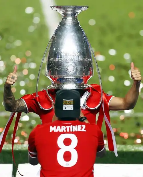 8月23日,拜仁慕尼黑队球员埃尔南德斯将冠军奖杯戴在头顶,庆祝夺冠.