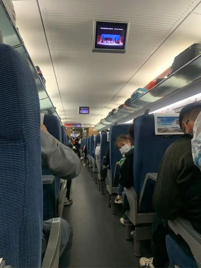 五一出游的动车上,这个同学正在吃方便面90,一个小朋友从车厢里路过