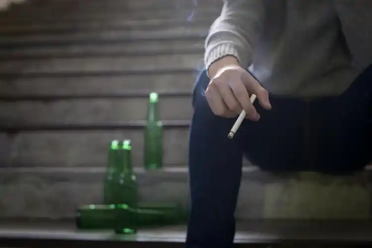 坐在地下的沮丧的人啤酒和香烟沮丧人物烦躁恼火烦躁无奈