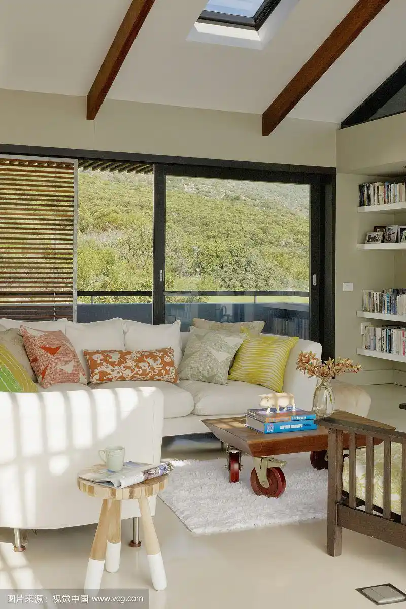 浅色沙发与图案分散靠垫靠在阳台窗户上,在现代客厅的视野