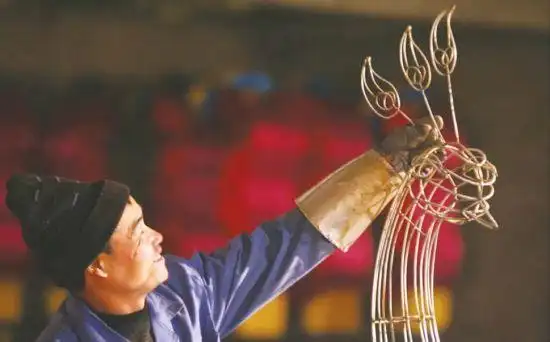 一名工人正在制作一只孔雀花灯的骨架.