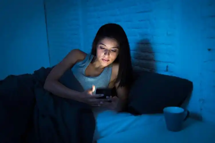 在深夜在黑暗的卧室躺在床上看手机放松