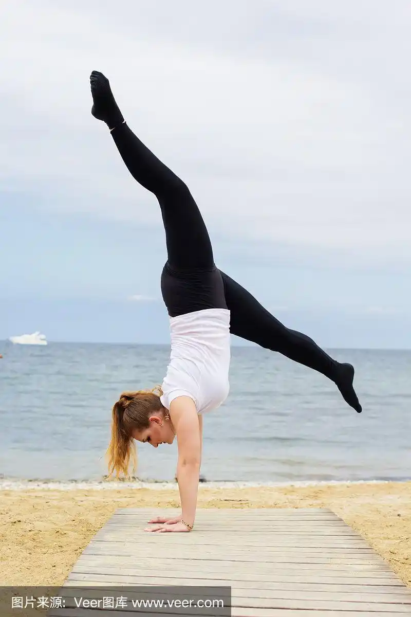 运动丰满的女人做倒立在海边