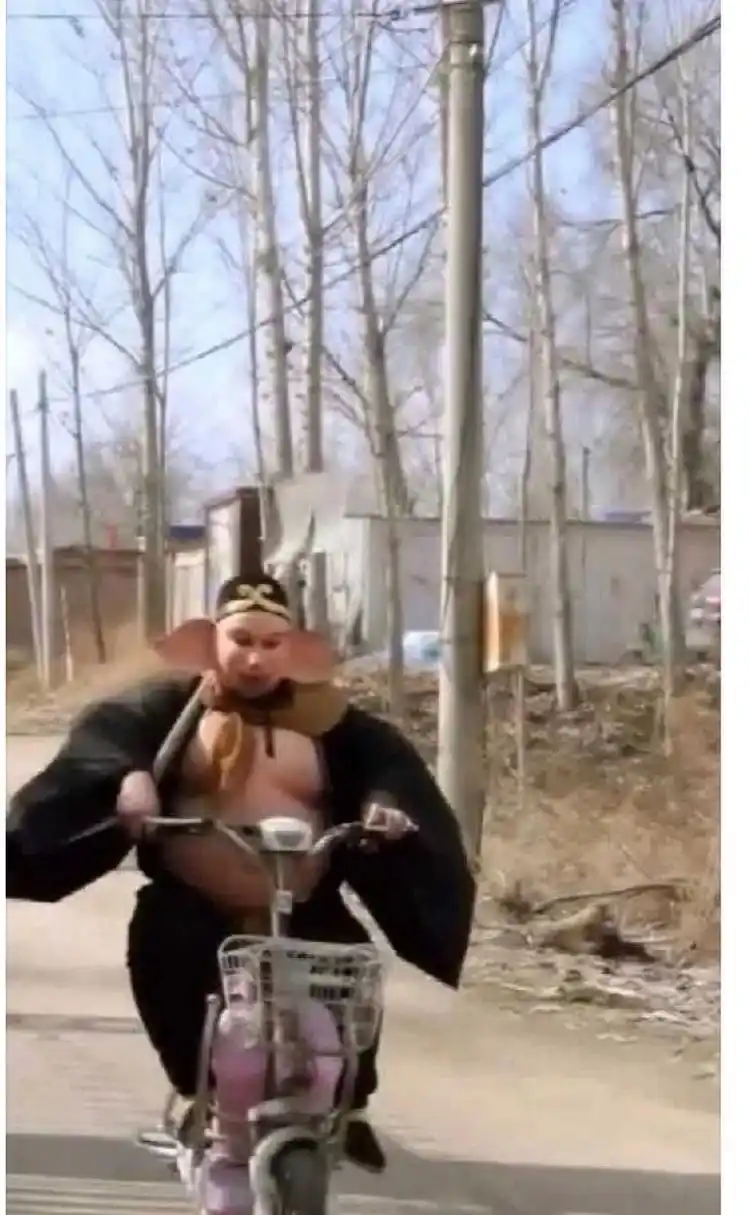 以下是 50 字左右文案:   这是猪八戒吗?竟骑着电动车,还扛着铲子!