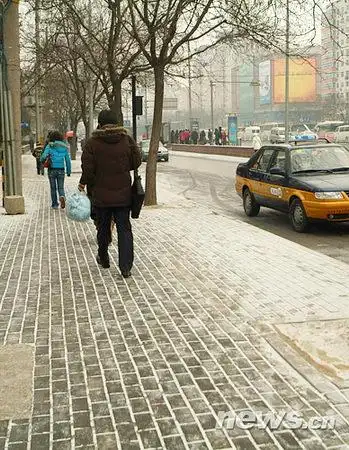 图文行人行走在小雪覆盖的人行道上