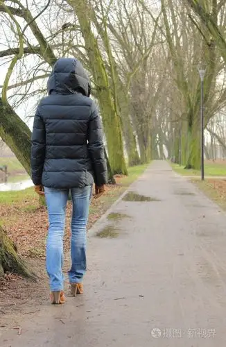 孤独的女子走在公园,在寒冷的雨天