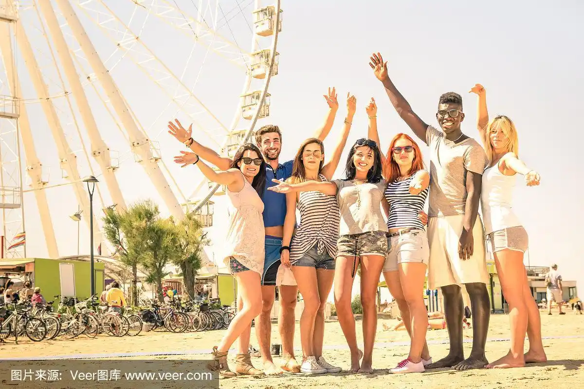 一群快乐的多种族朋友在海滩上欢呼
