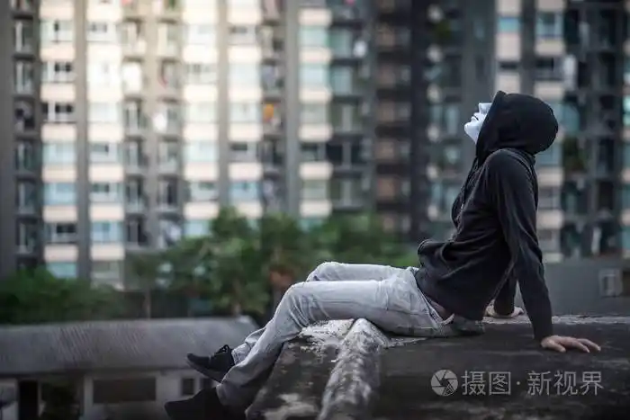 神秘男子在白色面具坐在屋顶上遗弃的buildi