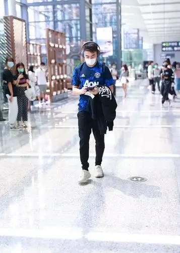 身穿蓝色t恤搭配运动裤的他造型清爽,戴耳机出街变街头帅小伙.