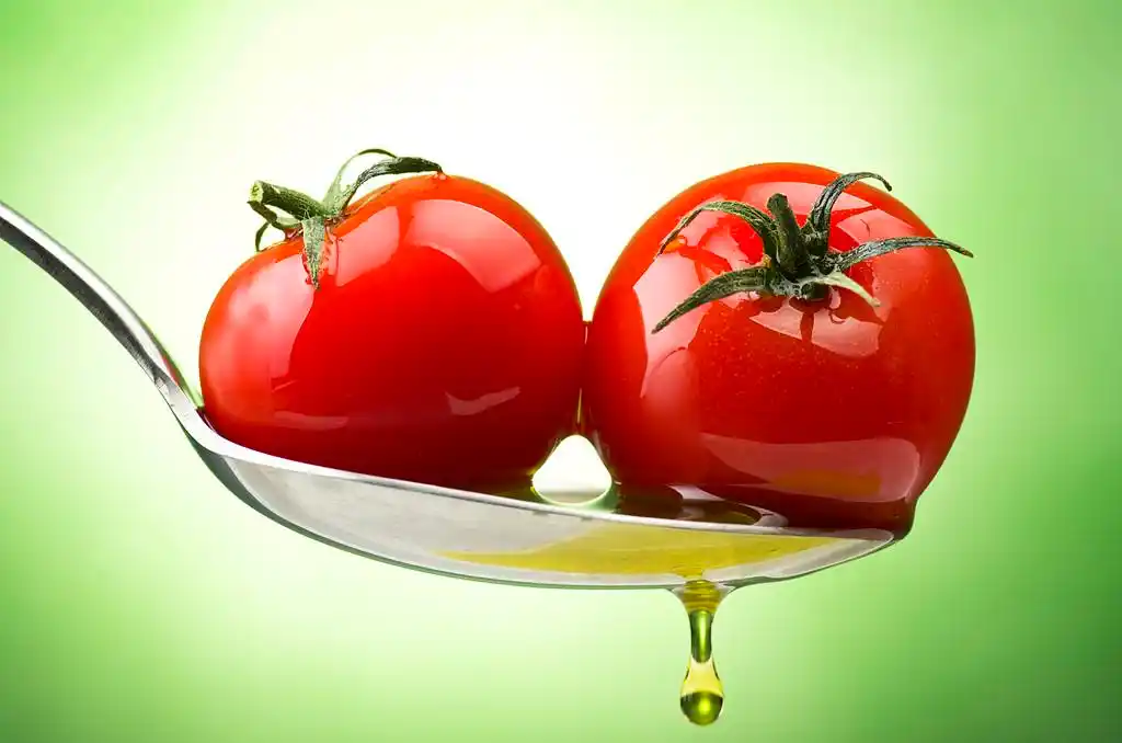 西红柿和油,与小西红柿和油的绿色背景的勺子