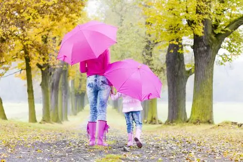 母亲和她的女儿在秋季小巷遮阳伞