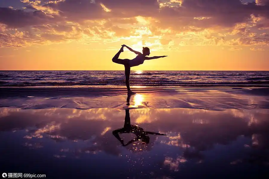 练瑜伽的女人日落时海滩上练瑜伽的女人的剪影
