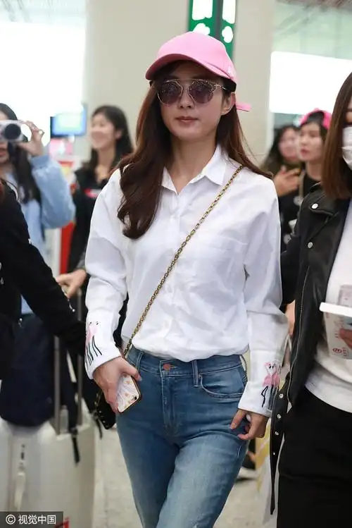 5月4日,赵丽颖与助理现身机场,她身穿火烈鸟白衬衣搭配牛仔裤,头戴