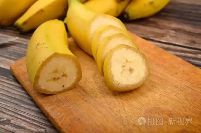 一根成熟的黄色香蕉在木质背景的木板上切成几块闭合