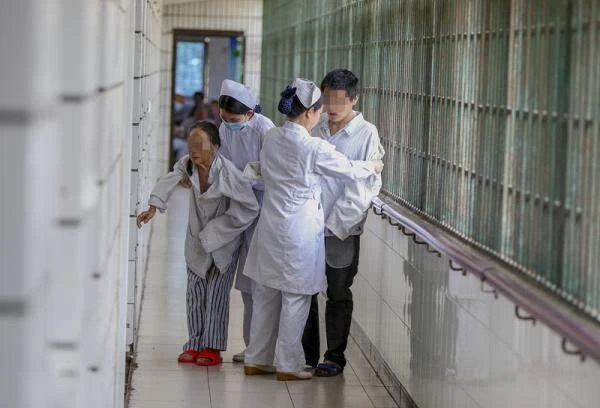 一精神病院,护士将行动不便,思维不清晰的病人带回房间.