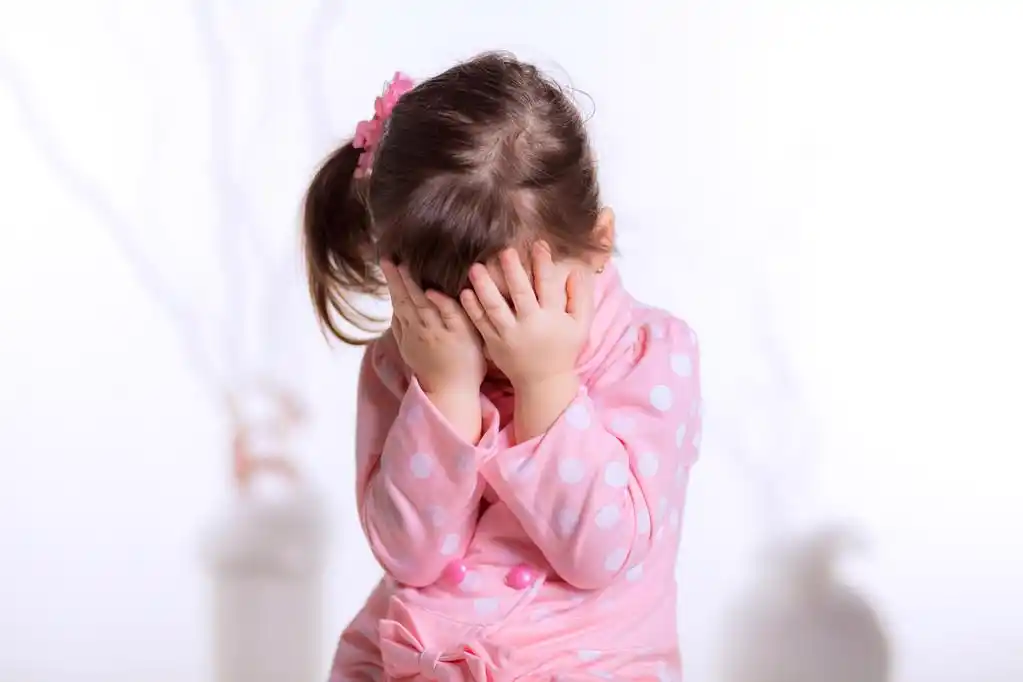 小女孩捂脸与手,可爱的小女孩,遮住脸,用双手,在白色的背景分离的肖像