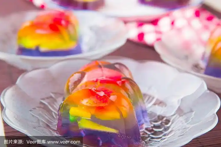 五彩缤纷的彩虹果冻放在透明的盘子里,配上糖,奶,白酱