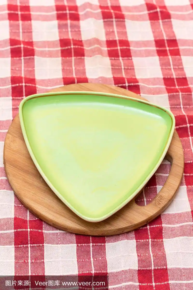 空白的三角形绿色盘子在木头和红色桌布上