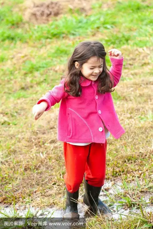 小女孩穿着雨靴在泥地里玩耍