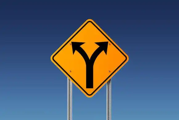 蓝色天空前面的黄色分岔路交通标志:分岔路和决策概念图片下载