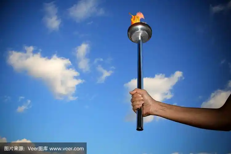 手握着燃烧着的火炬,火焰笼罩着多云的蓝天
