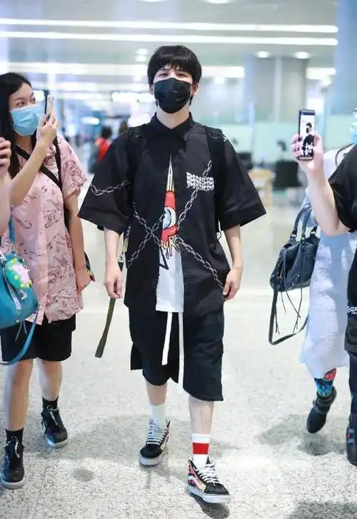 36岁大张伟低调走机场,穿印花t恤搭配锁链衬衫,顺毛发型有点乖