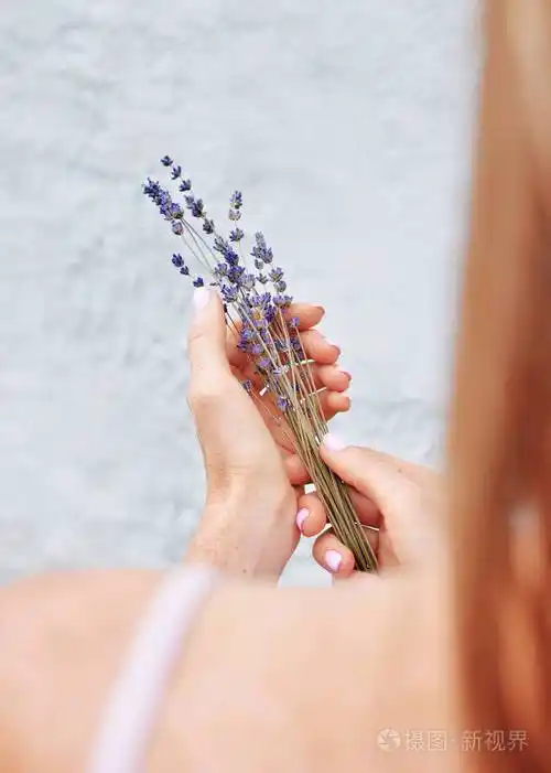 满脸雀斑的红发女孩手里拿着一束干枯的薰衣草花后视图