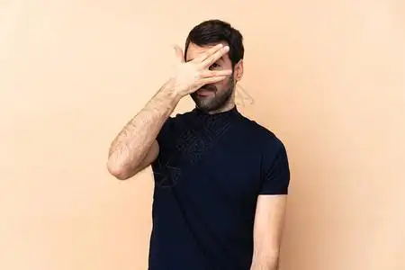 白人英俊帅男身陷孤立背景双手用眼蒙着双眼图片素材