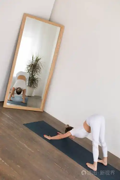 运动中的年轻女子在家里的白色背景下练习瑜伽