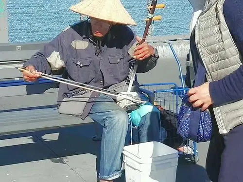 拉二胡的盲人  ,    曲目为《二泉映月》.