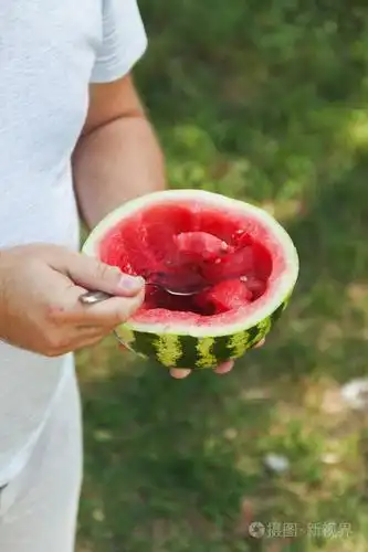 一名年轻男子正在用勺子吃西瓜概念