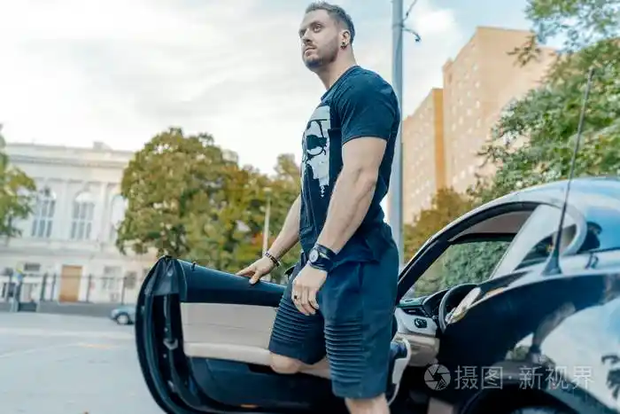 关闭的年轻迷人的男子下车的黑色汽车侧面视图