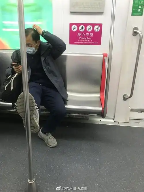 大叔坐地铁脚蹬扶手栏杆玩手机