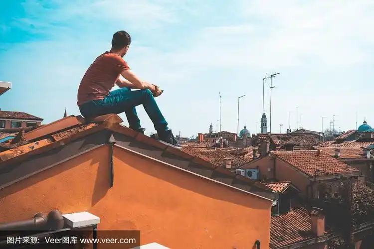 一个年轻人坐在意大利威尼斯的屋顶上.