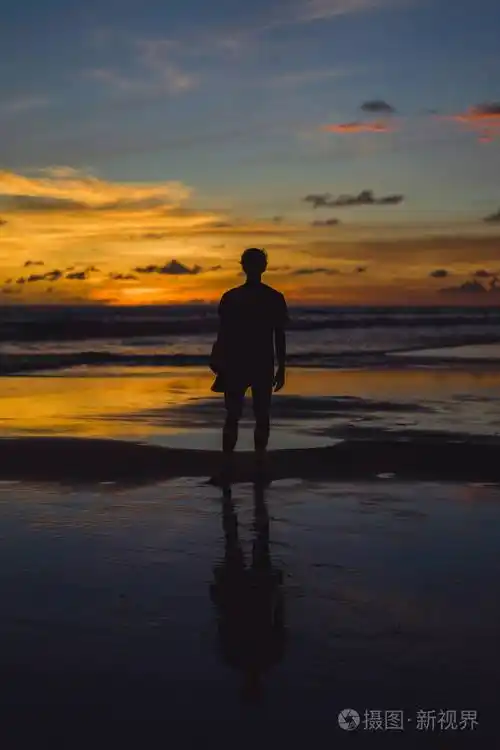 日落时海滩上的人那个女孩在夕阳的背景下跳跃