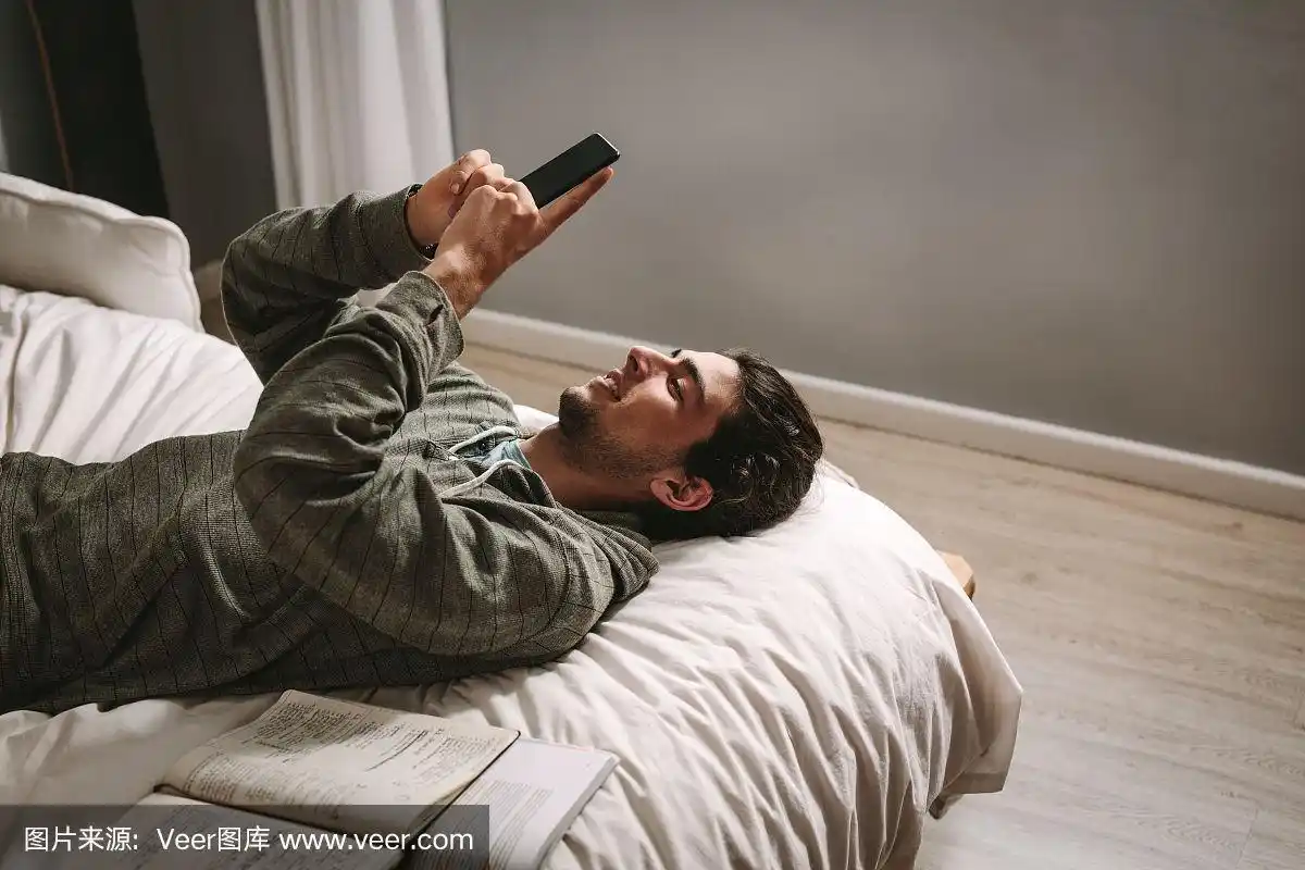 男人躺在床上看手机