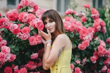 花园里玫瑰旁手上有纹身的美女.照片