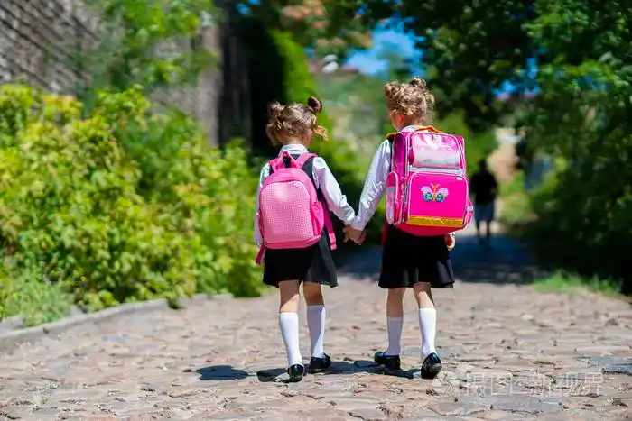 一个两个女生背着背包在小学外的背影孩子们放学回家研究结束夏天