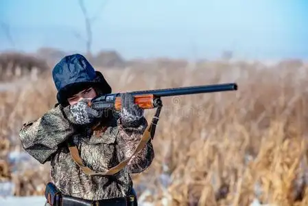 女性的猎人采用伪装衣服准备好的向打猎,hold采用g枪一照片