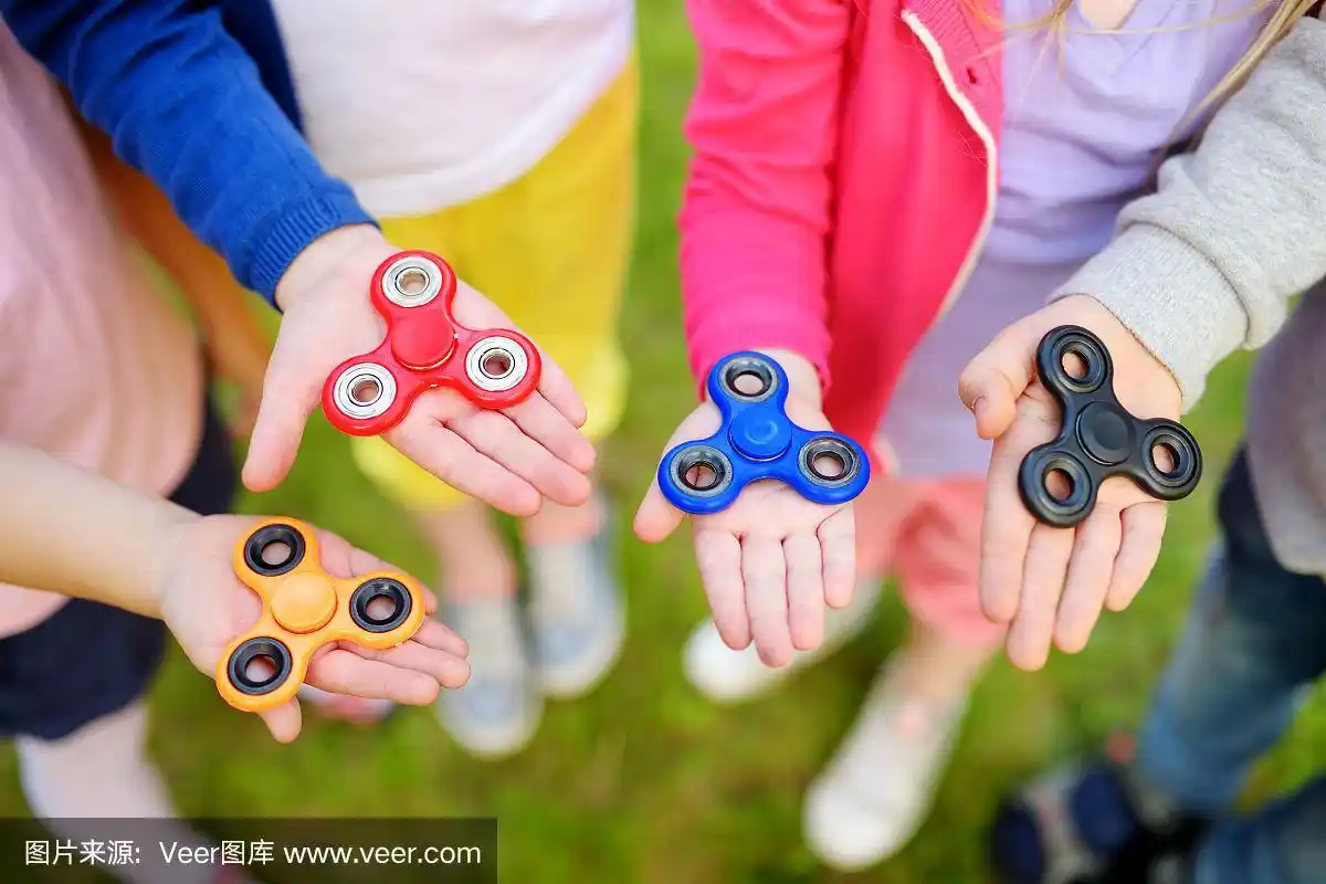四个孩子在操场上玩指尖陀螺.