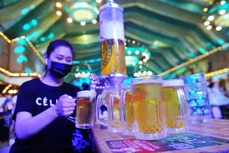 2020年8月1日,山东青岛啤酒节上,一名工作人员在给顾客送酒.