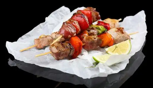 在黑色背景上的猪肉烤串照片