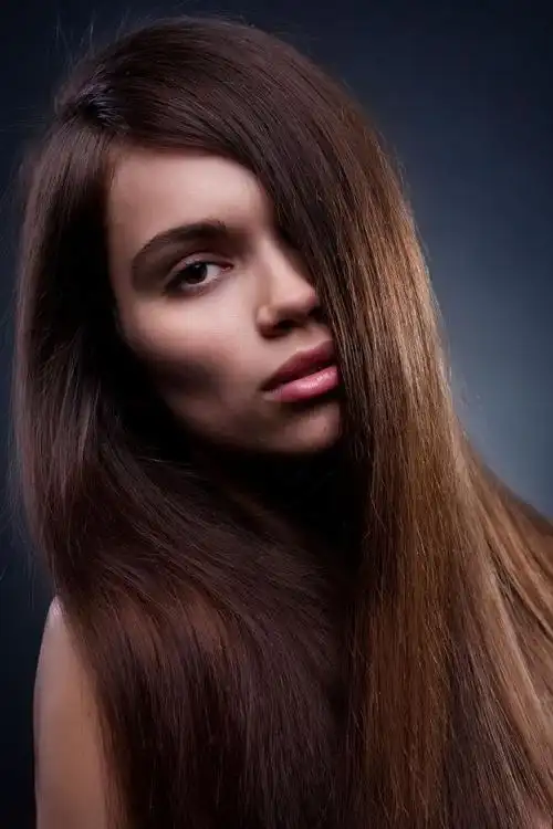 黑色背景下长着长长的黑色直发的年轻美女