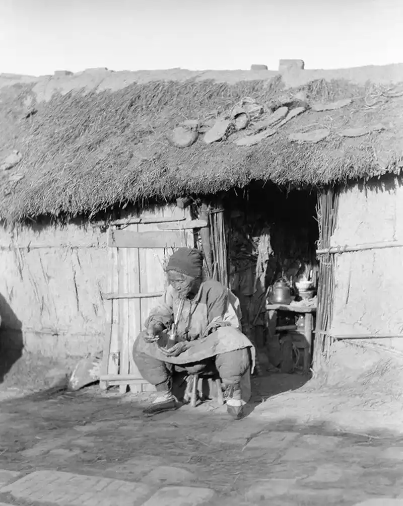 茅草屋前的老奶,旧社会这样的房屋很常见