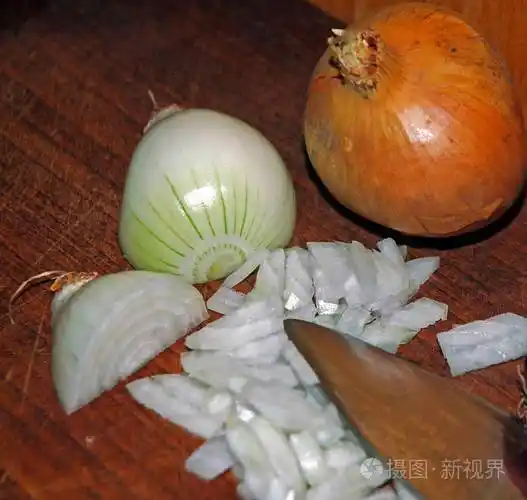 柚木砧板上的白洋葱部分切成块带皮