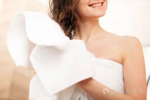 洗完澡后,一位微笑的年轻女士用毛巾擦拭头发