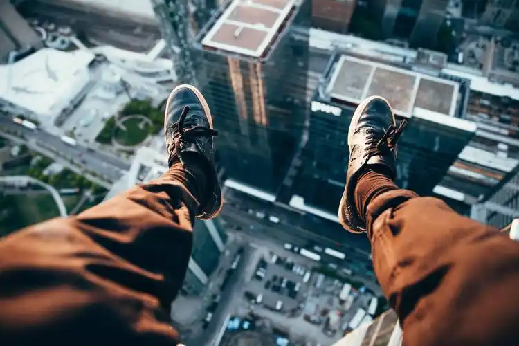 on edge of building with feet hanging overlooking the city